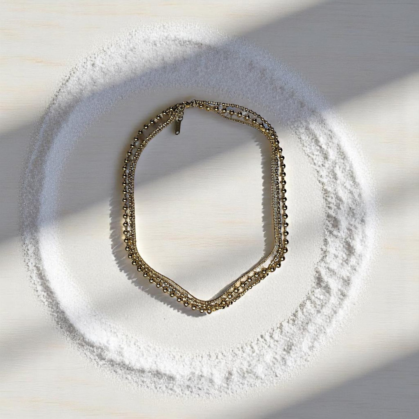 Collar dorado y topos exhibidos sobre mesa clara con decoración minimalista