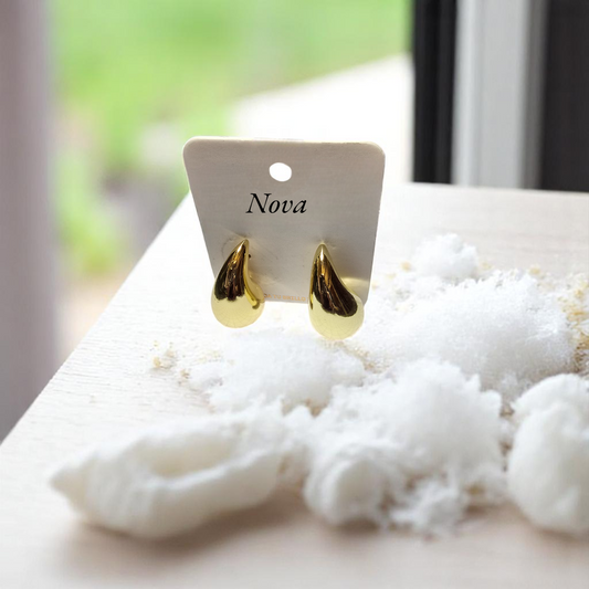 Aretes dorados en forma de gota lisa Nova sobre fondo de algodón