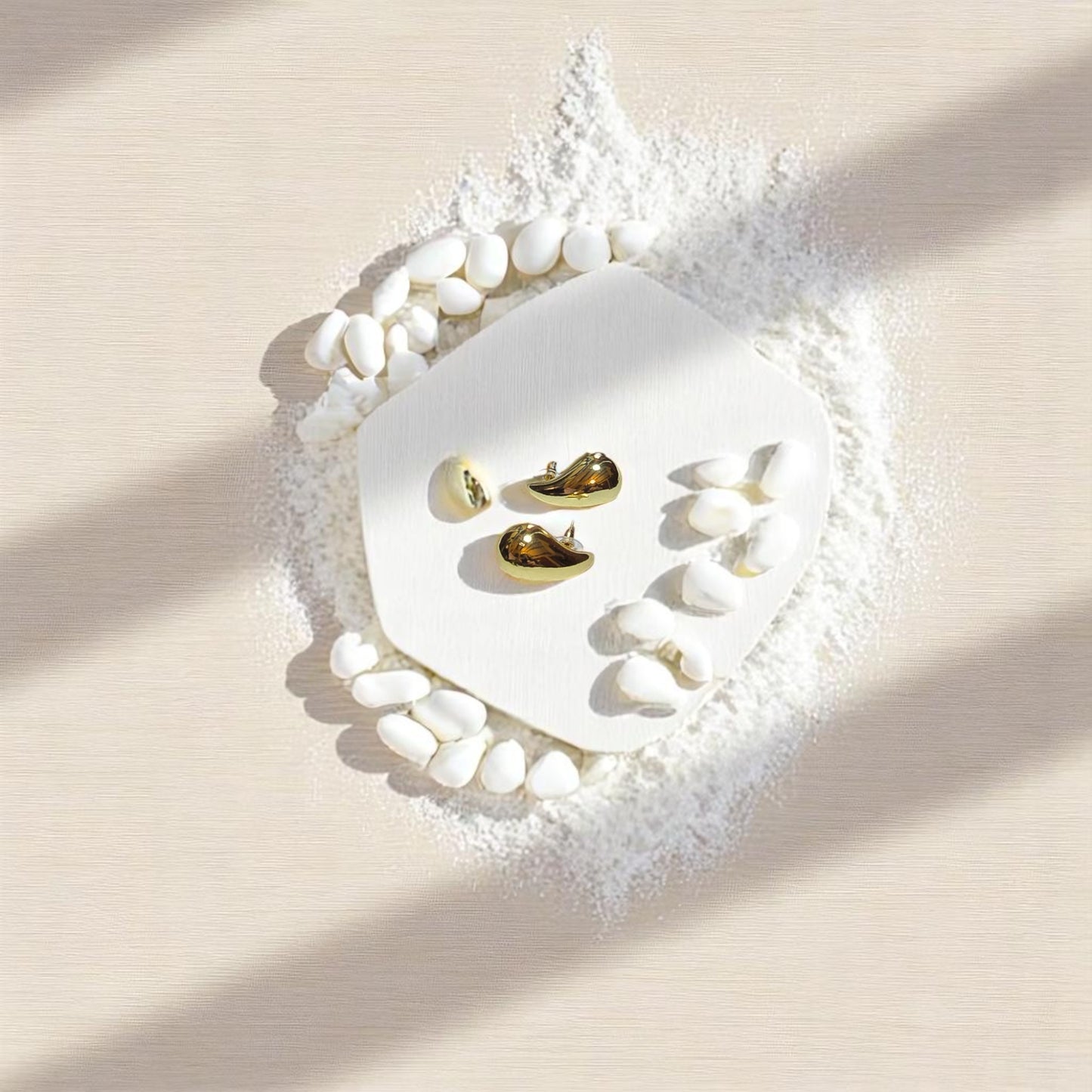 Aretes dorados en forma de gota lisa Nova sobre fondo de algodón