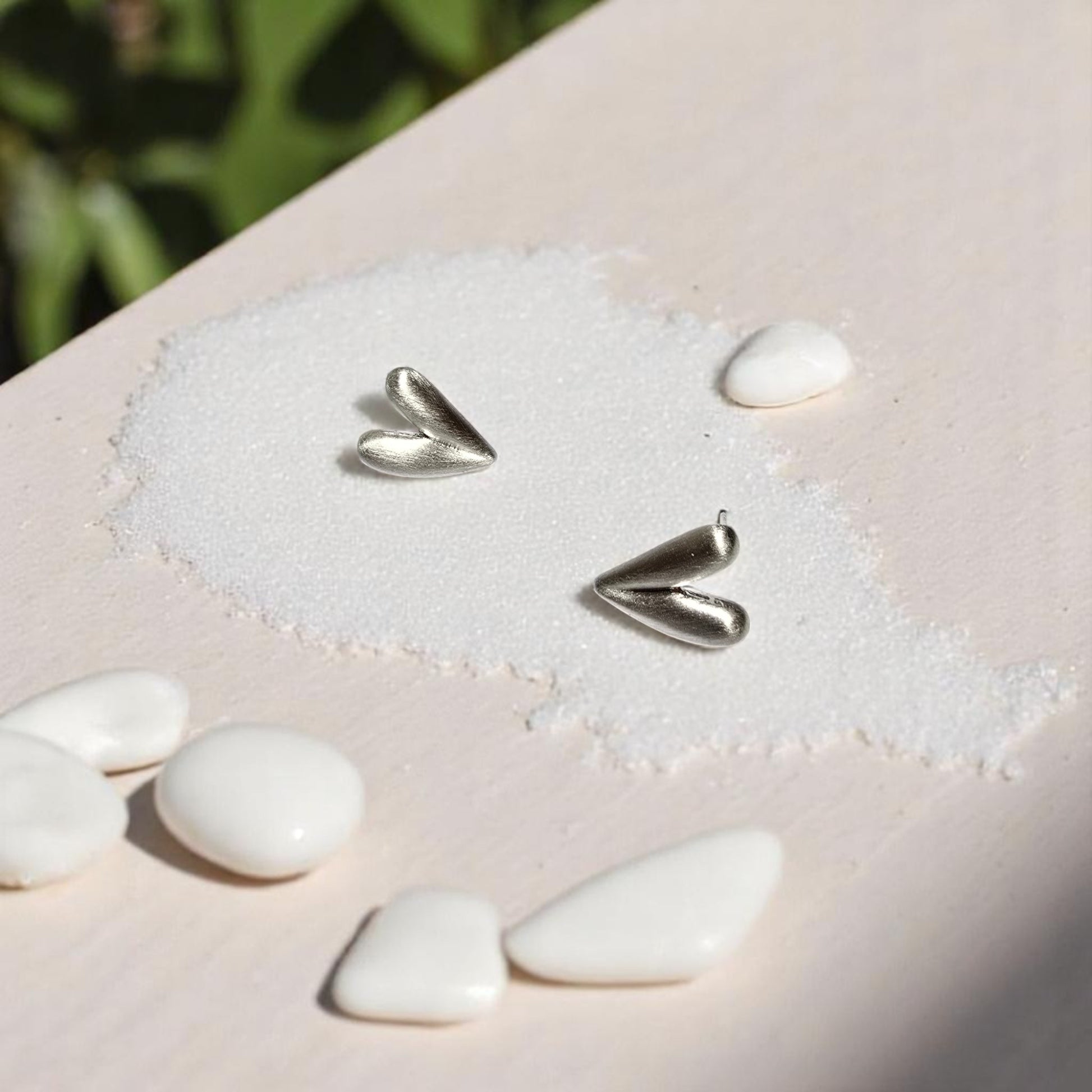 Aretes corazón plateado Nova con fondo de playa