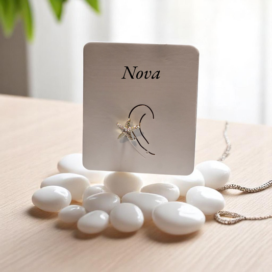 Earcuff de estrella de mar en plata con circonias brillando sobre arena blanca