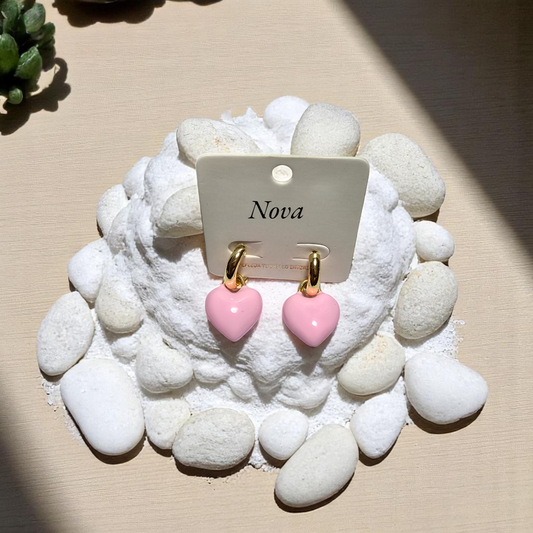 Aretes de corazón rosa esmaltado sobre fondo de piedras blancas
