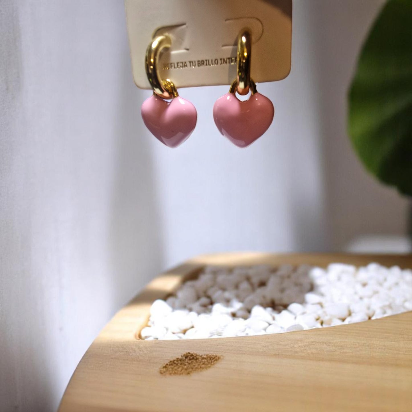 Vista cercana de aretes de acero inoxidable dorado con colgantes en forma de corazón rosa