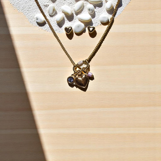 Detalle de broche con charms y cadena bañada en oro