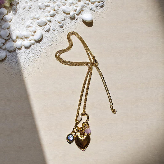 Collar dorado con dije de corazón y cristal azul sobre fondo de madera clara