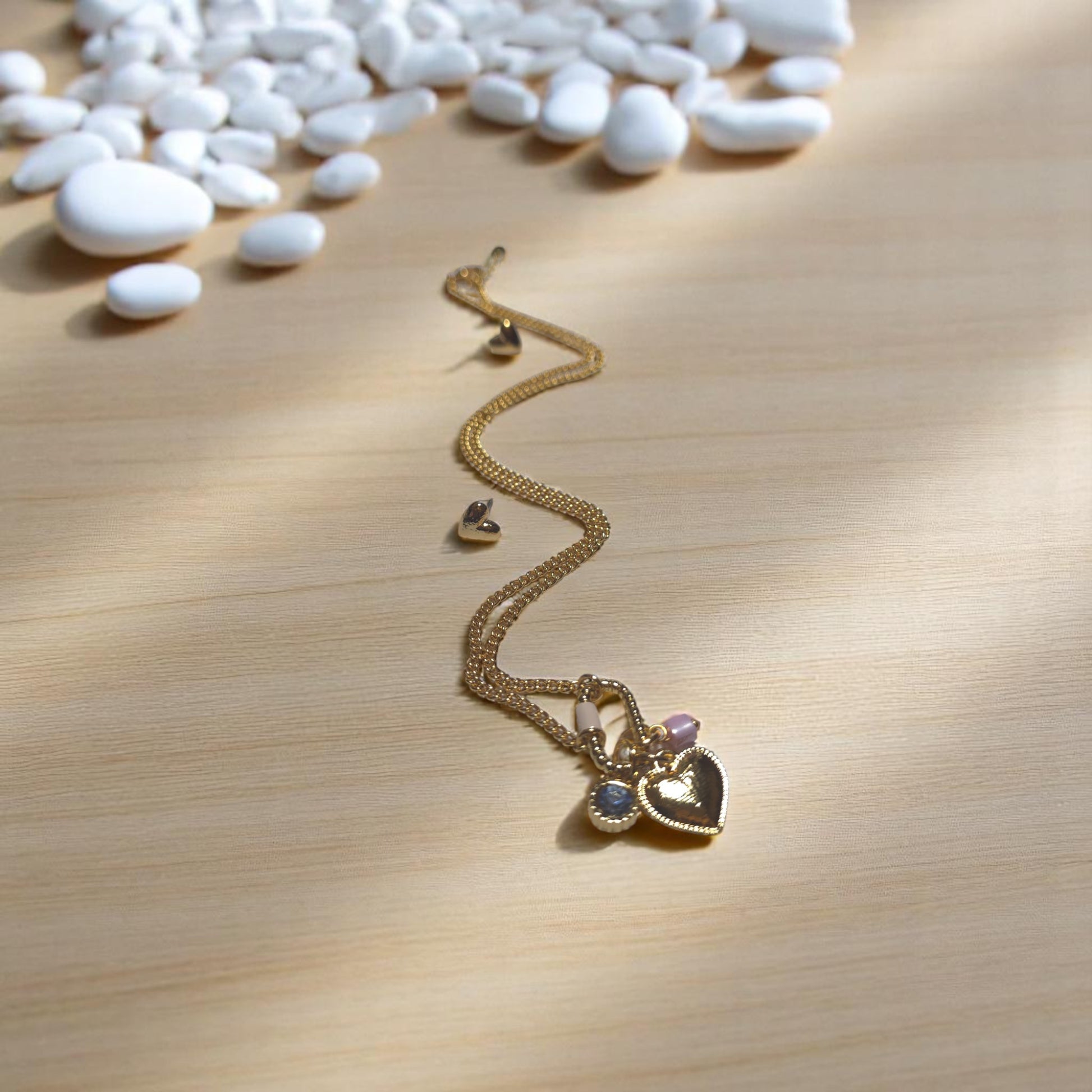 Detalle de broche con charms y cadena bañada en oro
