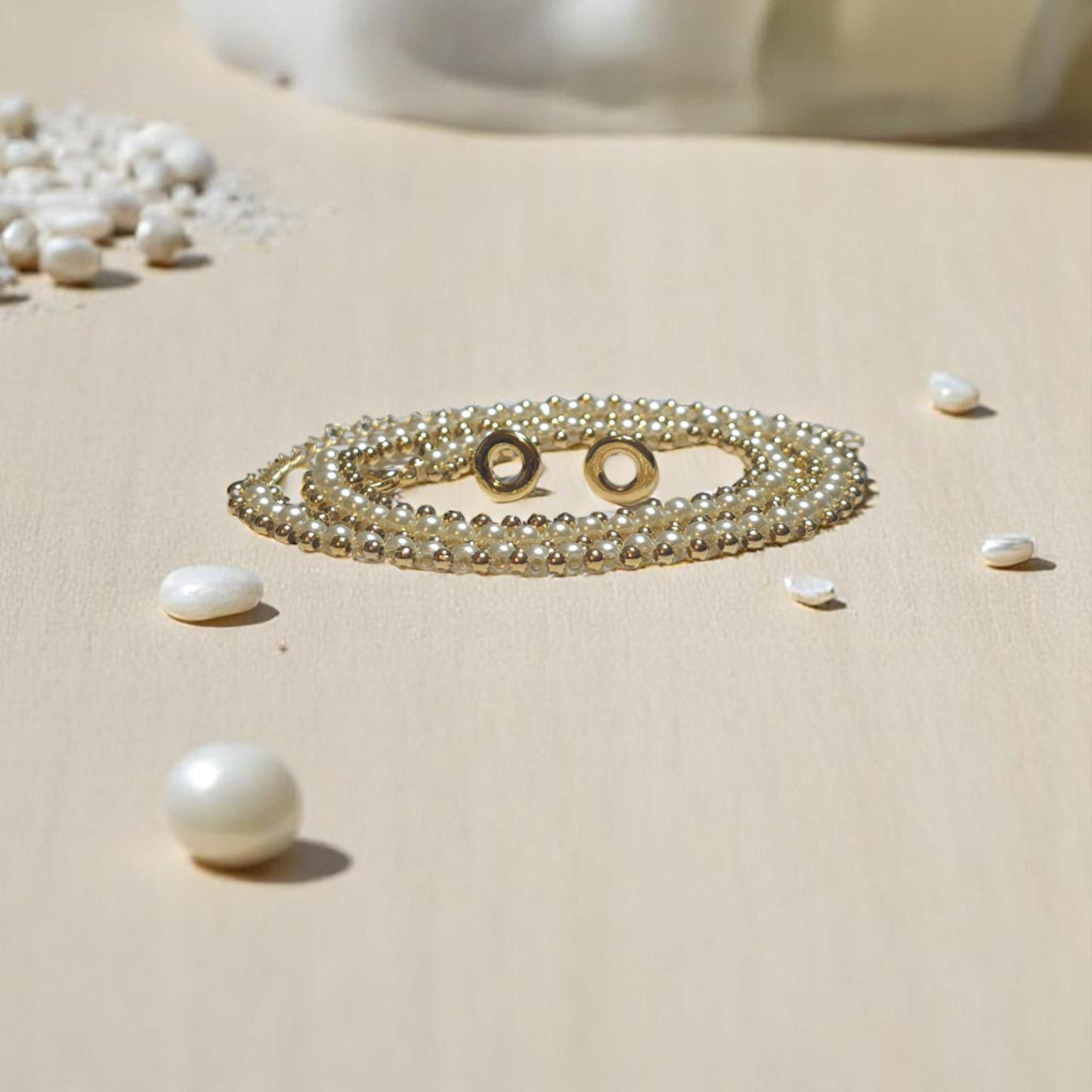 Choker doble de perlas blancas con broche bañado en oro sobre fondo beige