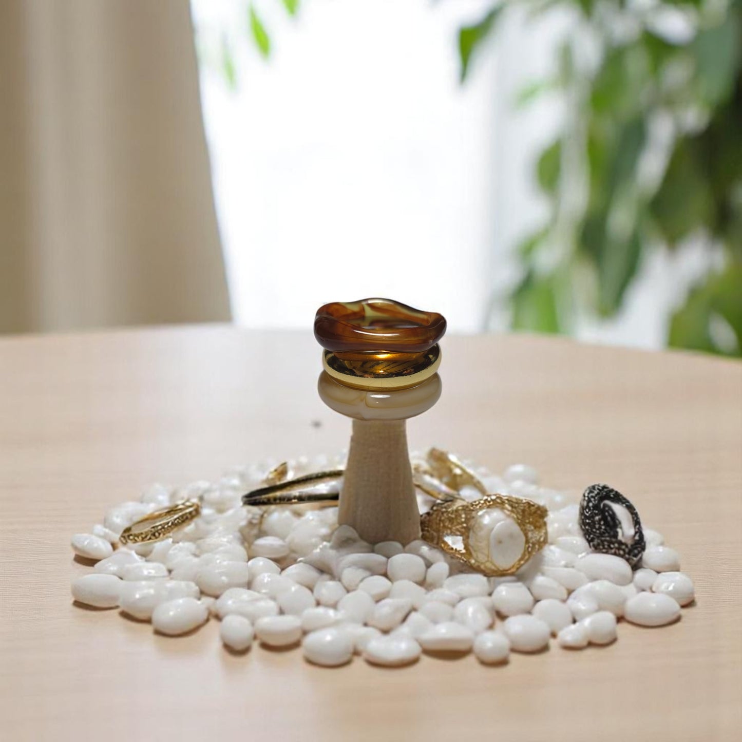 Anillos apilados en composición zen sobre mesa de madera clara