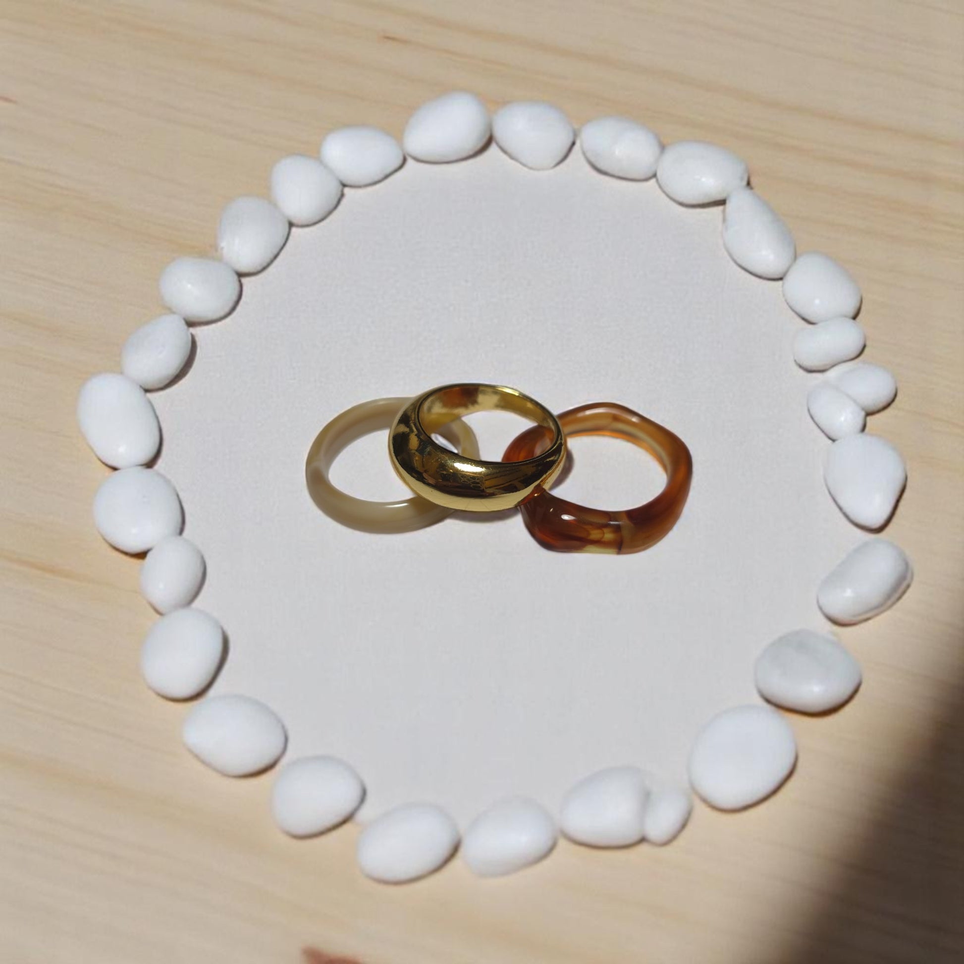 Anillos dorado, crema y caramelo en disposición vertical sobre soporte