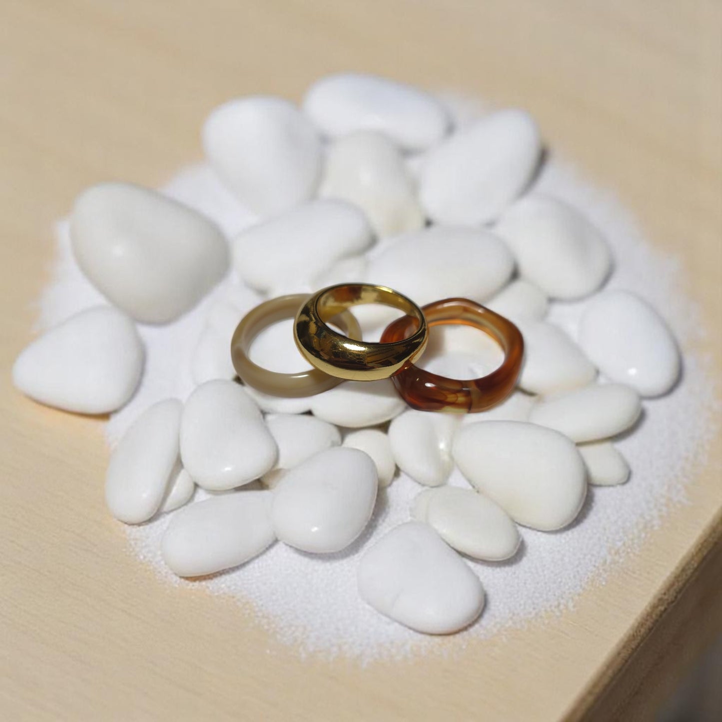 Anillos dorado, crema y caramelo en disposición vertical sobre soporte