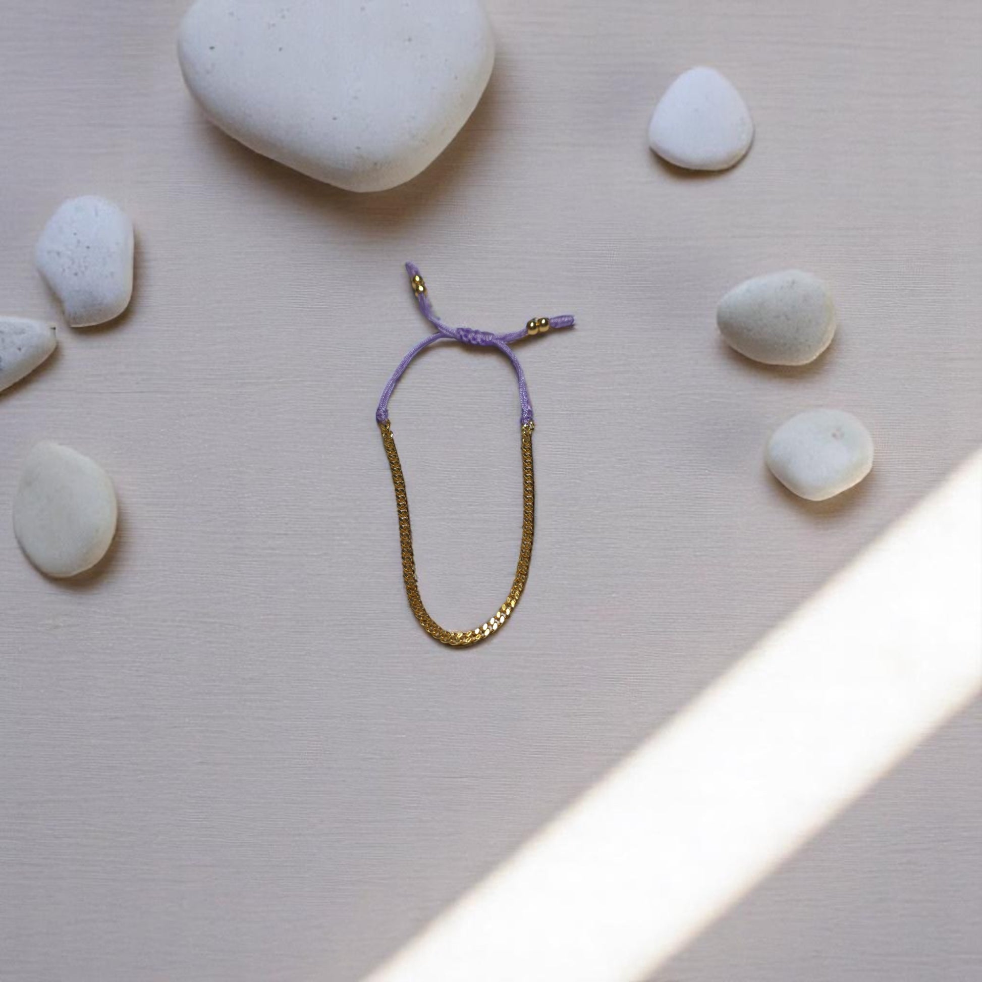 Pulsera ajustable morada con dije de corazón dorado rodeada de piedras blancas