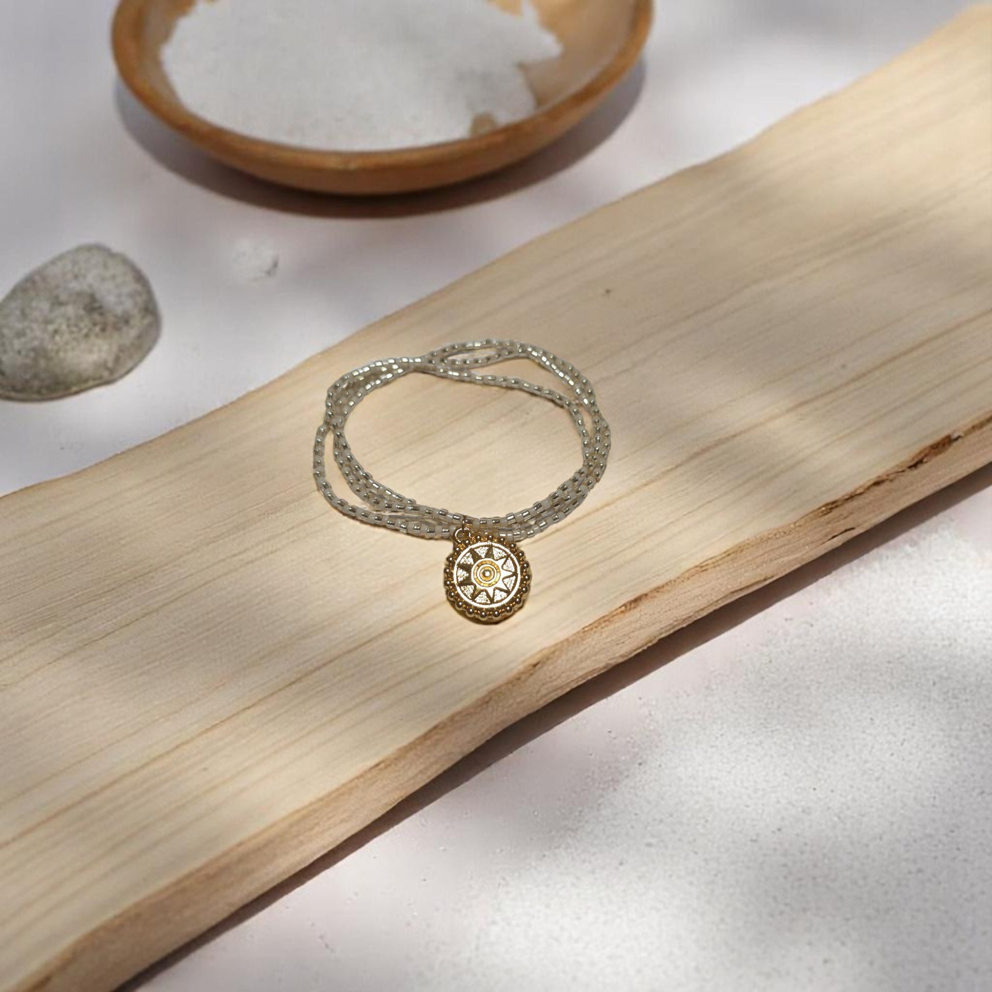 Pulsera de cadena dorada con hilo lila en fondo claro con sombras suaves