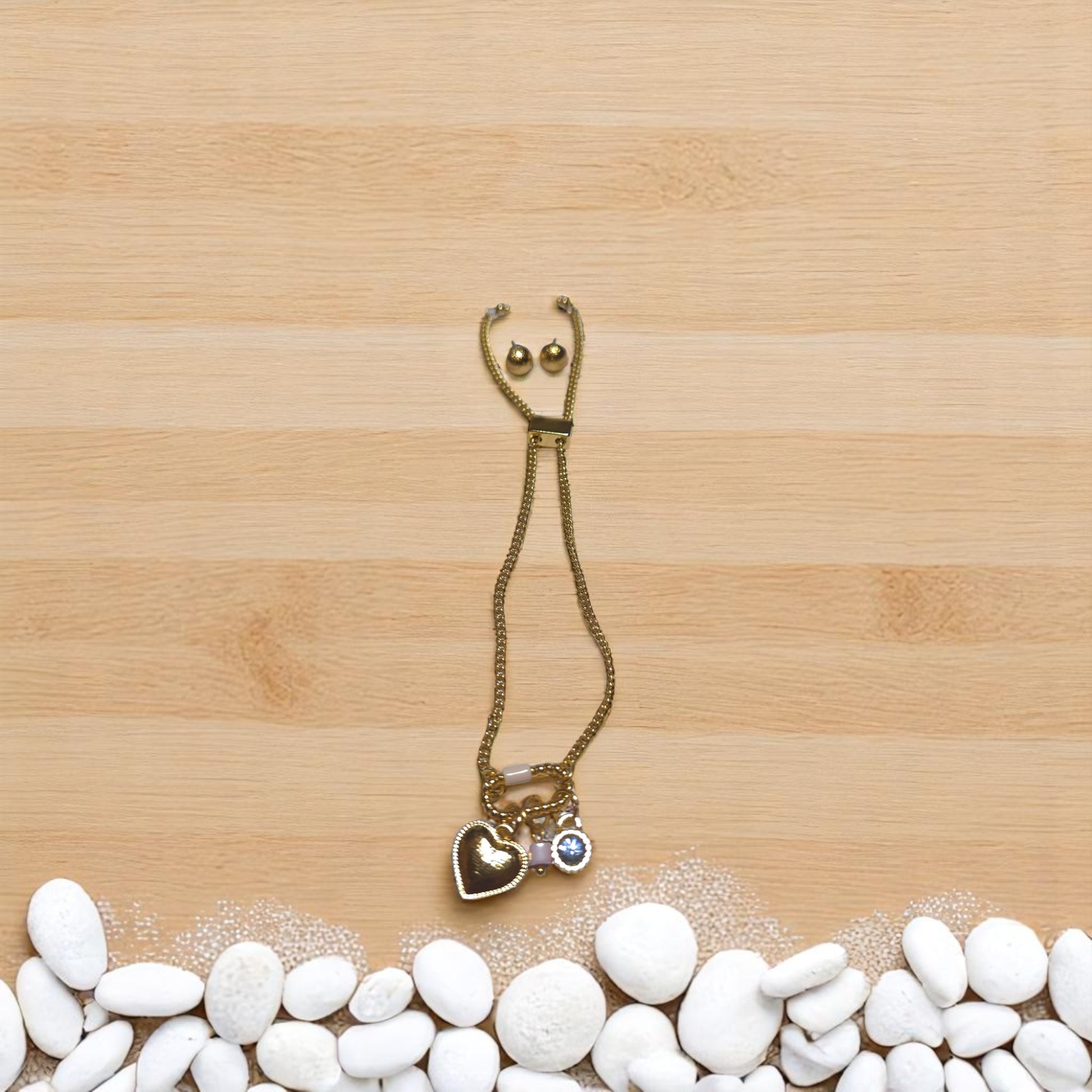 Conjunto Nova formado por pulsera con dijes y aretes pequeños presentado en círculo de piedras