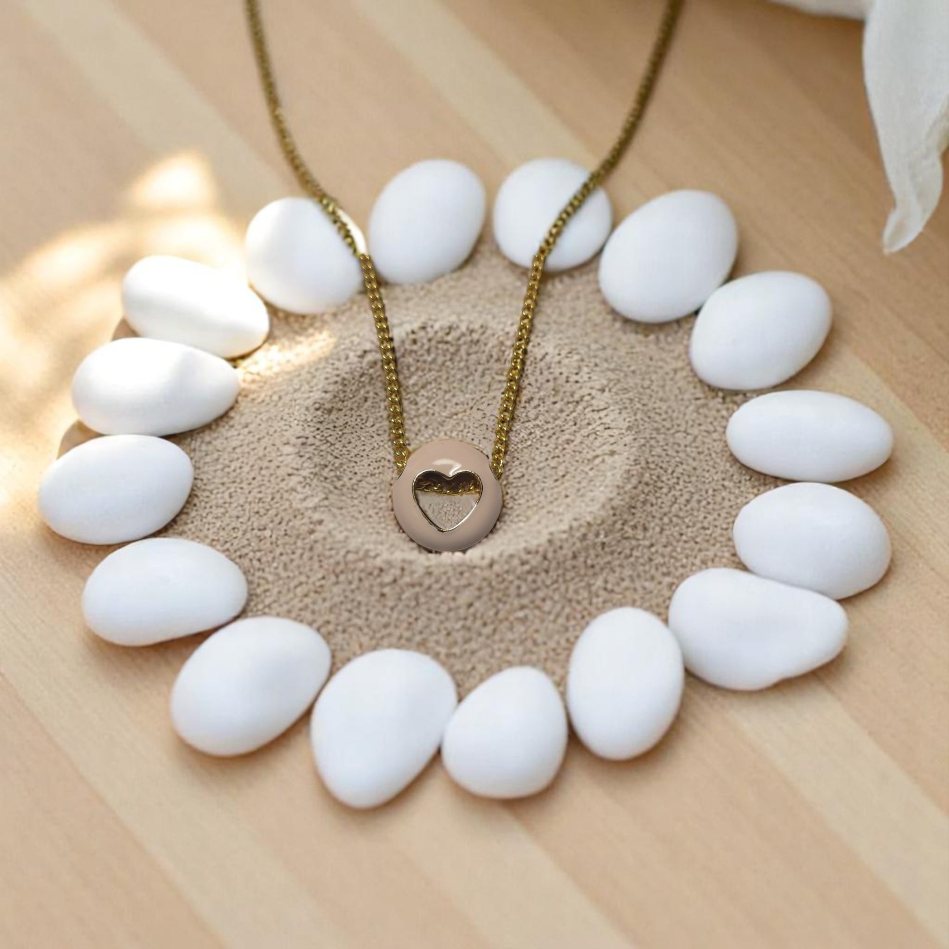 Set de collares layering dorados con dijes de corazón y aretes en fondo natural