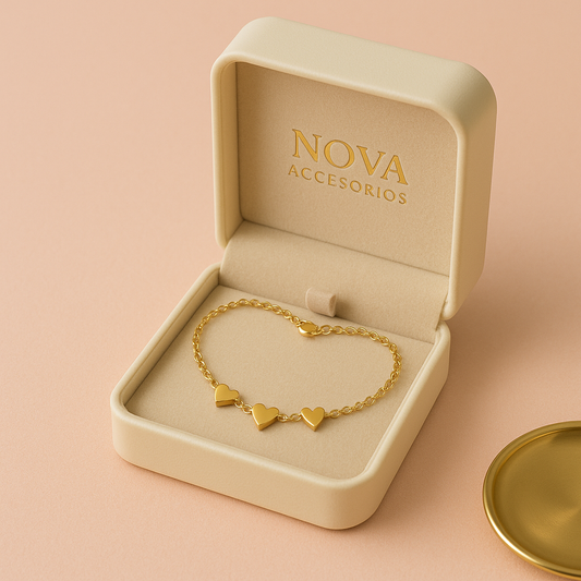 Detalle de pulsera fina dorada con dijes de corazón en distintos tamaños