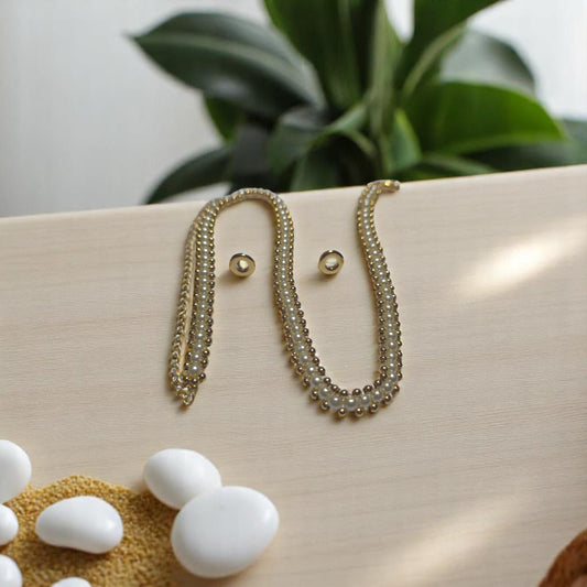 Choker doble de perlas blancas con broche bañado en oro sobre fondo beige