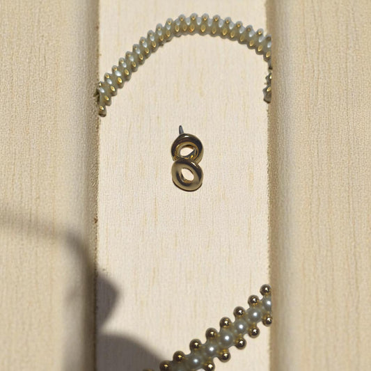 Collar artesanal de perlas cultivadas y pendientes dorados en mesa de madera clara