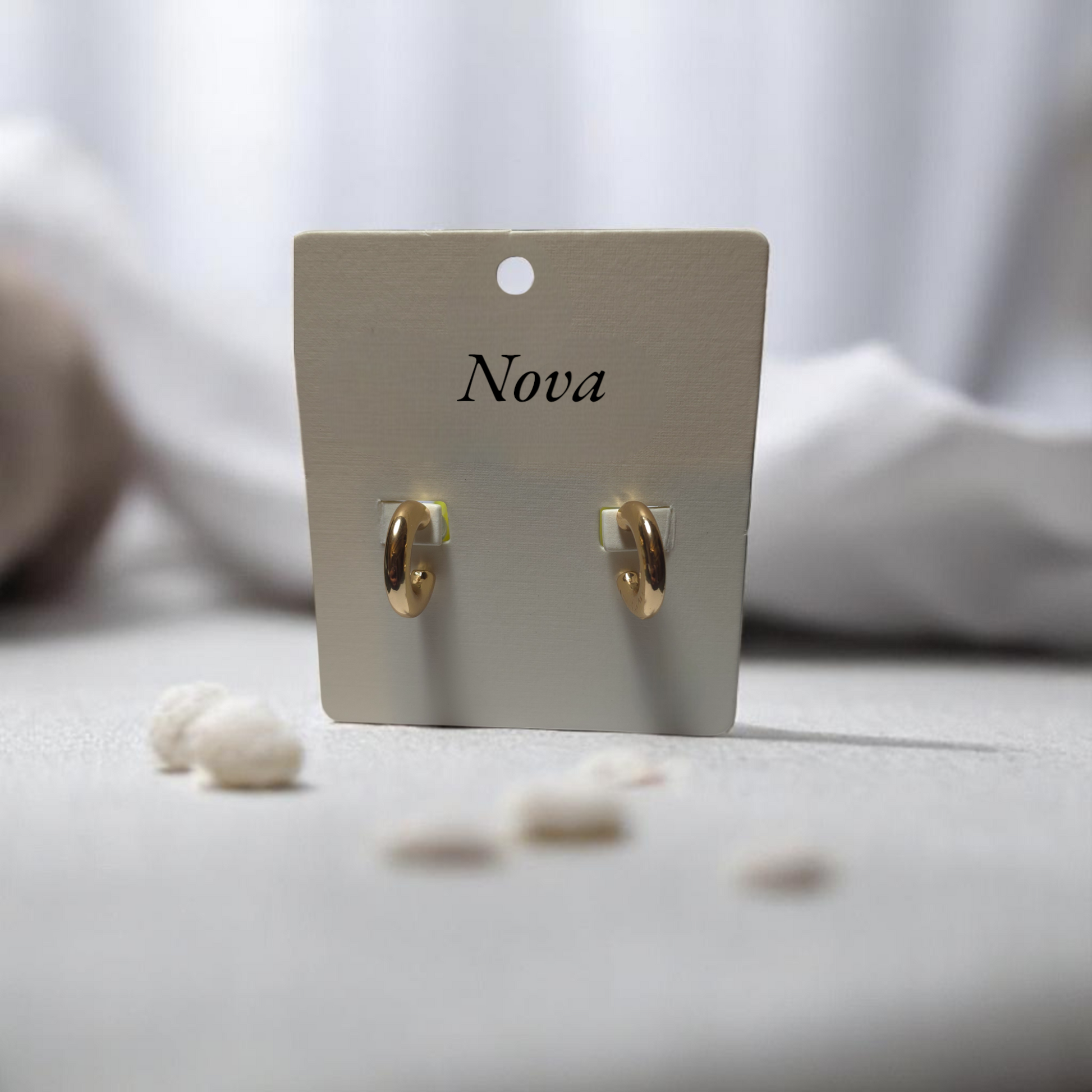 Aretes tipo candonga dorada pequeña con fondo neutro